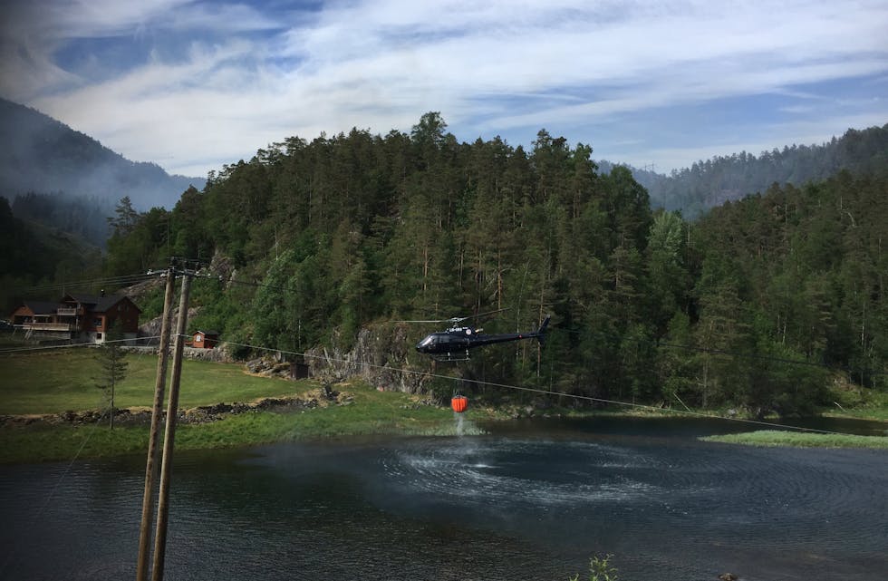 Helikopteret kjører i skyttertrafikk mellom elva og skogen der det brenn. Foto: Frank Waal.
