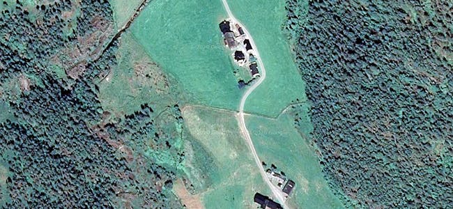 Dette satellittbildet viser dei to gardsbruka som har kommunal veg tett på gardstuna. Bebuarane ønsker ny vegtrasé forbi gardsbruka, langs skogbeltet på høgre side. 