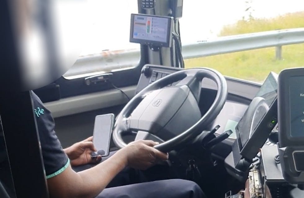 Her blir sjåføren filma medan han scrollar og leser på mobilen sin.