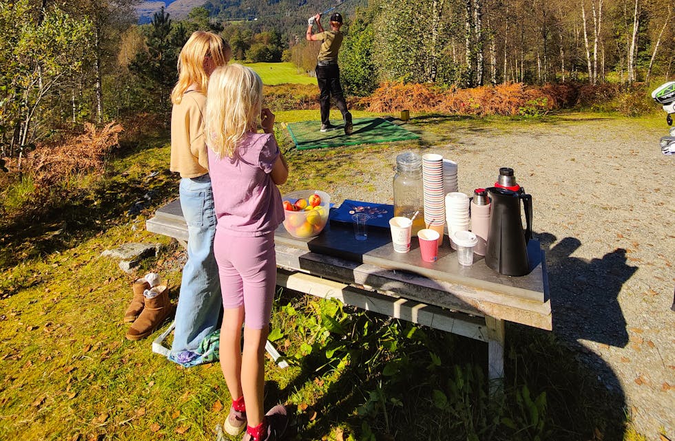 Åtteåringane Oda Olava Vikedal og Sofie Djuv Nilsen samla inn heile 1000 kroner til barnekreftsaka ved å selge drikke og epler til golfspelarar laurdag. Her er det Ulrik Hodne som slår ut på hol 4.